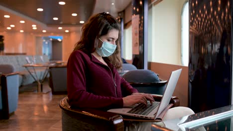 mujer con máscara trabajando en una computadora portátil en un crucero