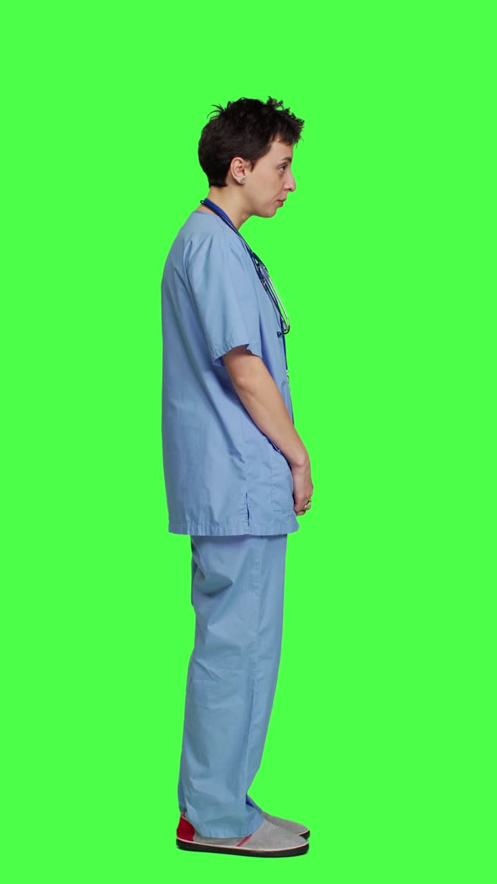 Profile Cheerful smiling medical assistant standing against greenscreen backdrop