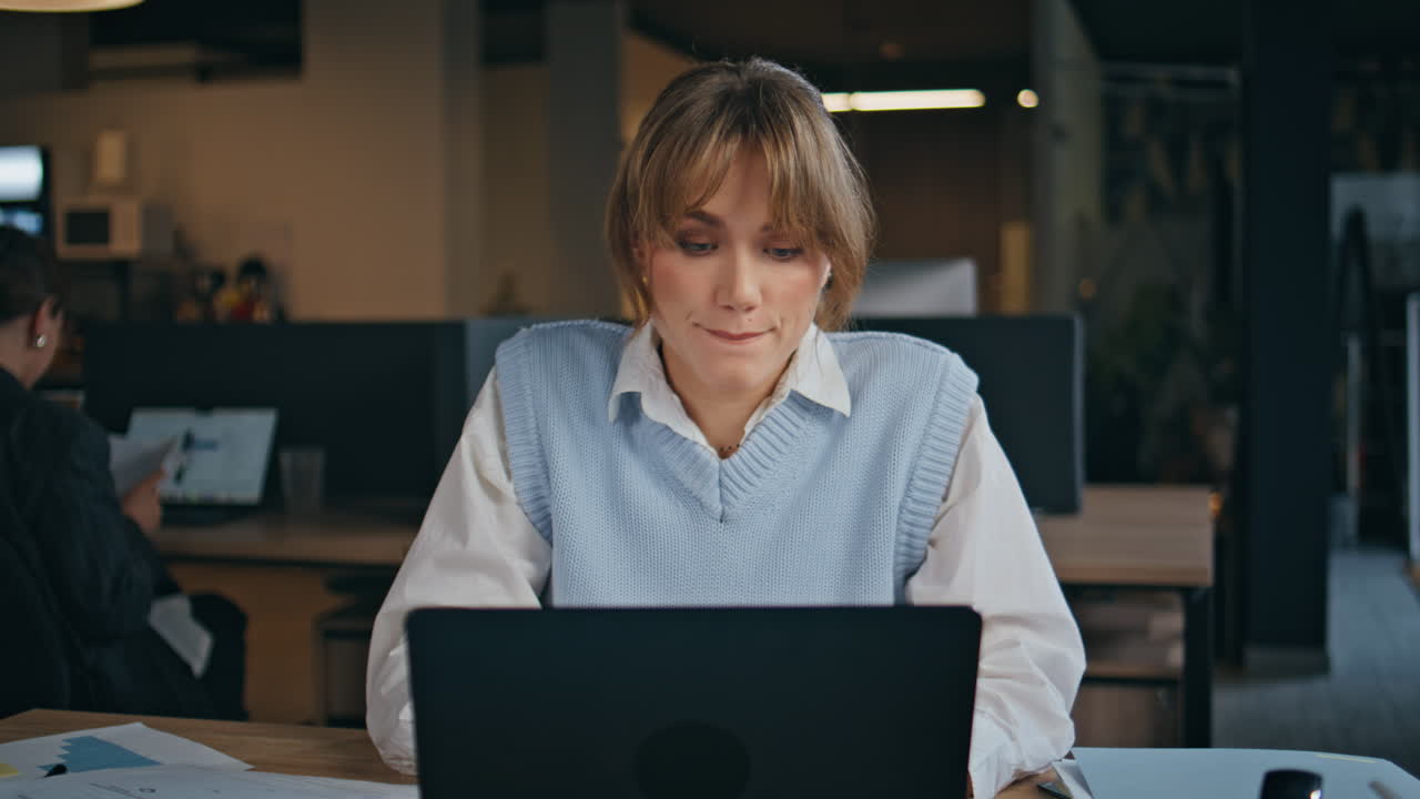 Impiegata aziendale che digita al computer in un open space, primo piano. Donna che consulta documenti