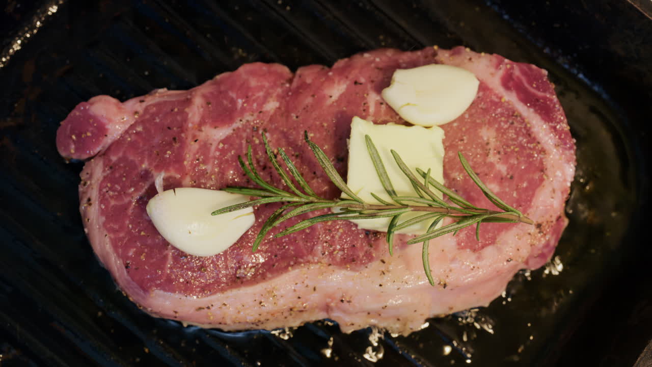 Spicchi d'aglio e burro aggiunti a una bistecca mentre cuoce su una padella grill