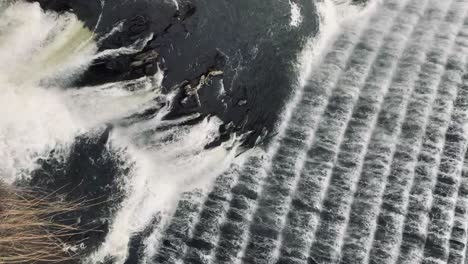 waterfall-on-the-side-of-croton-damn-in-New-York,-dark-water-and-rocks