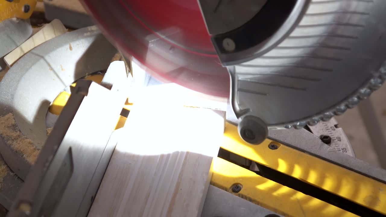 красивый молодой плотник использует круговую пилу при установке дерева в строительстве нового дома