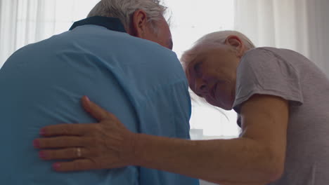 Close-Up-Of-Worried-Retired-Senior-Couple-Sitting-On-Bed-At-Home-Talking-Together