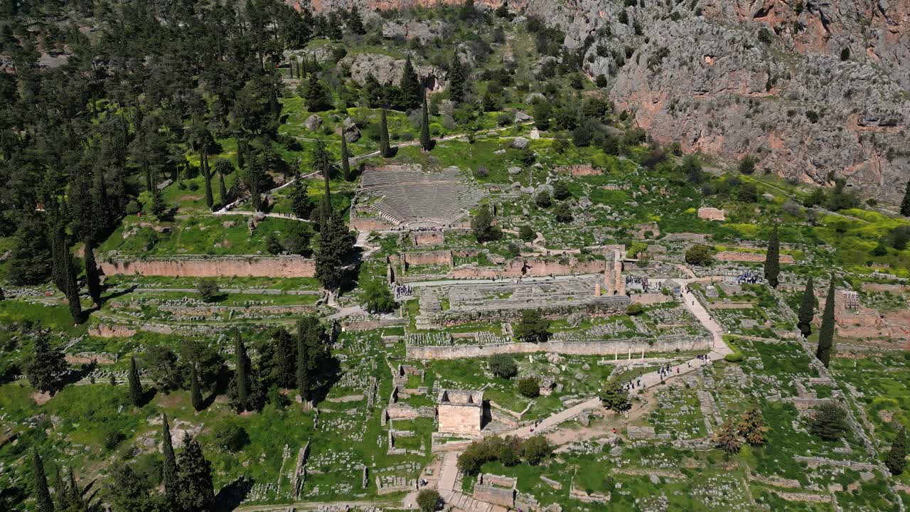 Drone flyover of Delphi amphitheatre and Temple of Apollo with surrounding Greek terrain