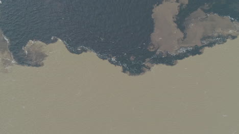water from negro river and solimoes river meeting in the amazon, aerial shot, mixing, texture