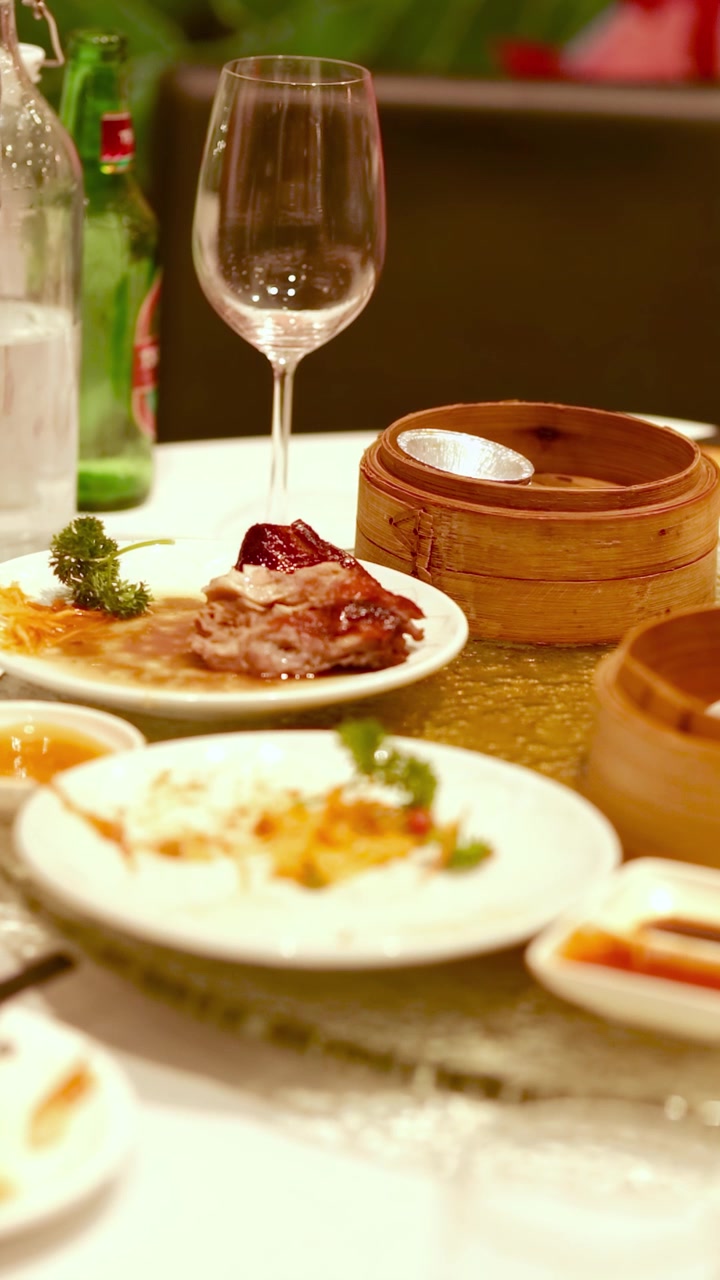 A beautifully set table with Chinese dishes, dim sum, and elegant glassware, creating a warm and inviting dining atmosphere