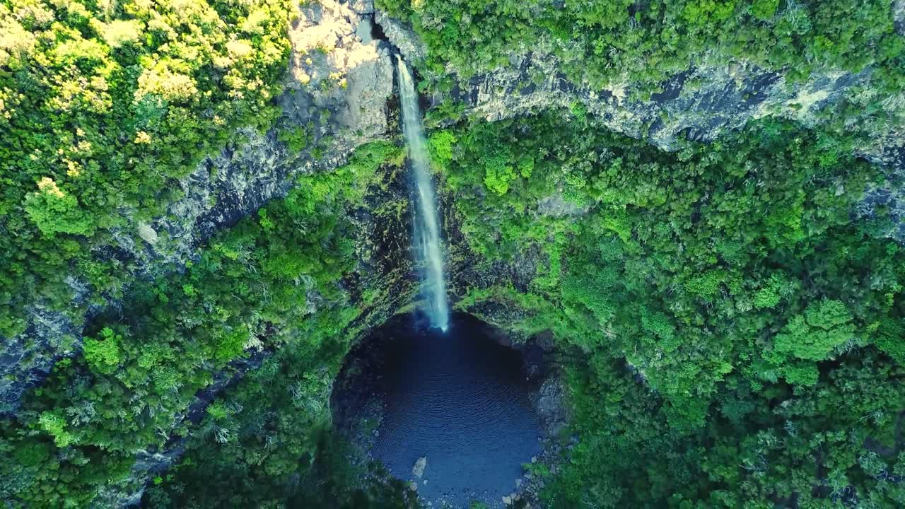 Stunning aerial perspective of Cascata do Risco waterfall in Madeira, surrounded by lush green cliffs and cascading into a serene pool below, highlighting the island's natural beauty