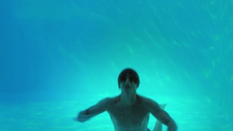 happy man jumping in swimming pool waving at camera