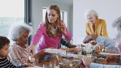 Multi-Generation-Family-Enjoying-Meal-Sitting-Around-Table-At-Home-Together