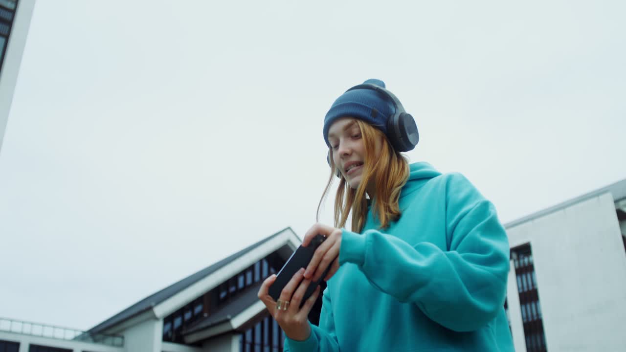 Teenagepige, der spiller på telefon med hovedtelefoner