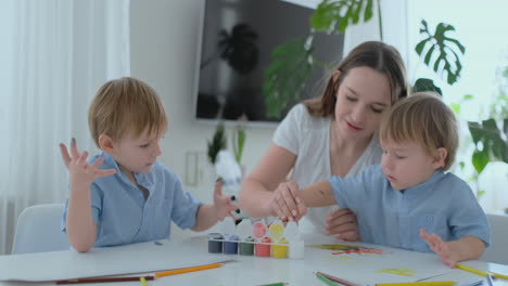 dos hijos de varones y una madre se dedican al desarrollo creativo haciendo tareas con los dedos en el papel. el desarrollo de las sensaciones táctiles y las matemáticas pequeñas.