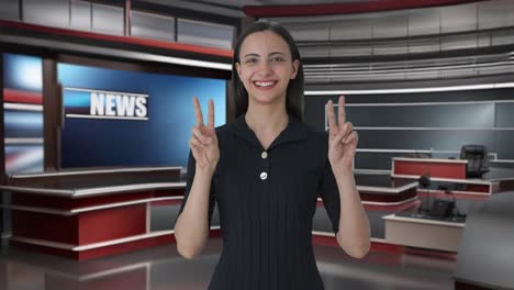 happy indian female news anchor showing victory sign