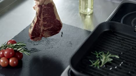 chef preparing meat at griddle. closeup man hands putting steak at grill.