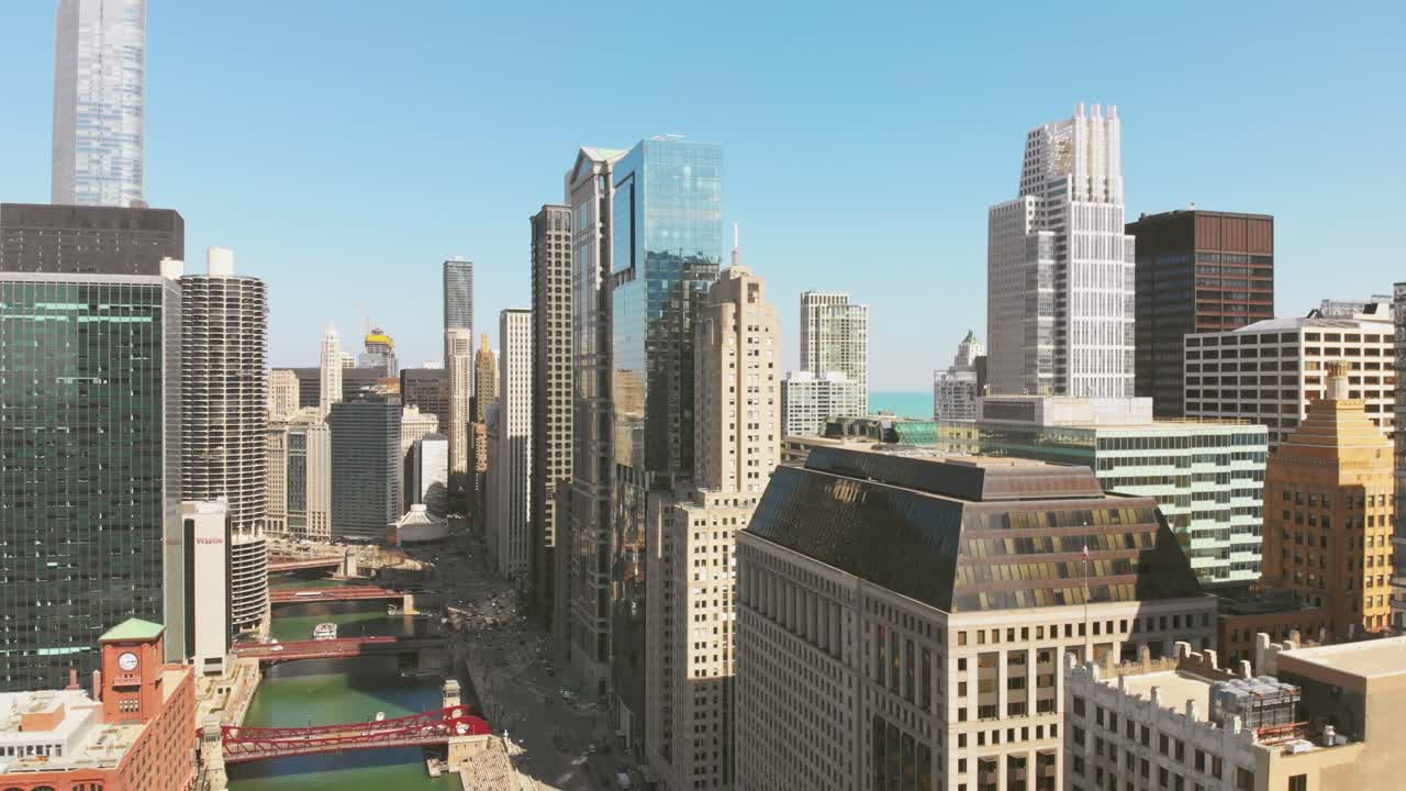 Vista aérea do centro de Chicago com densos edifícios de escritórios altos, prédios à beira do rio e várias pontes sobre o rio sob um céu azul claro