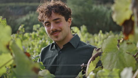 portrait grape plantation worker standing at vineyard alone. happy winegrower.