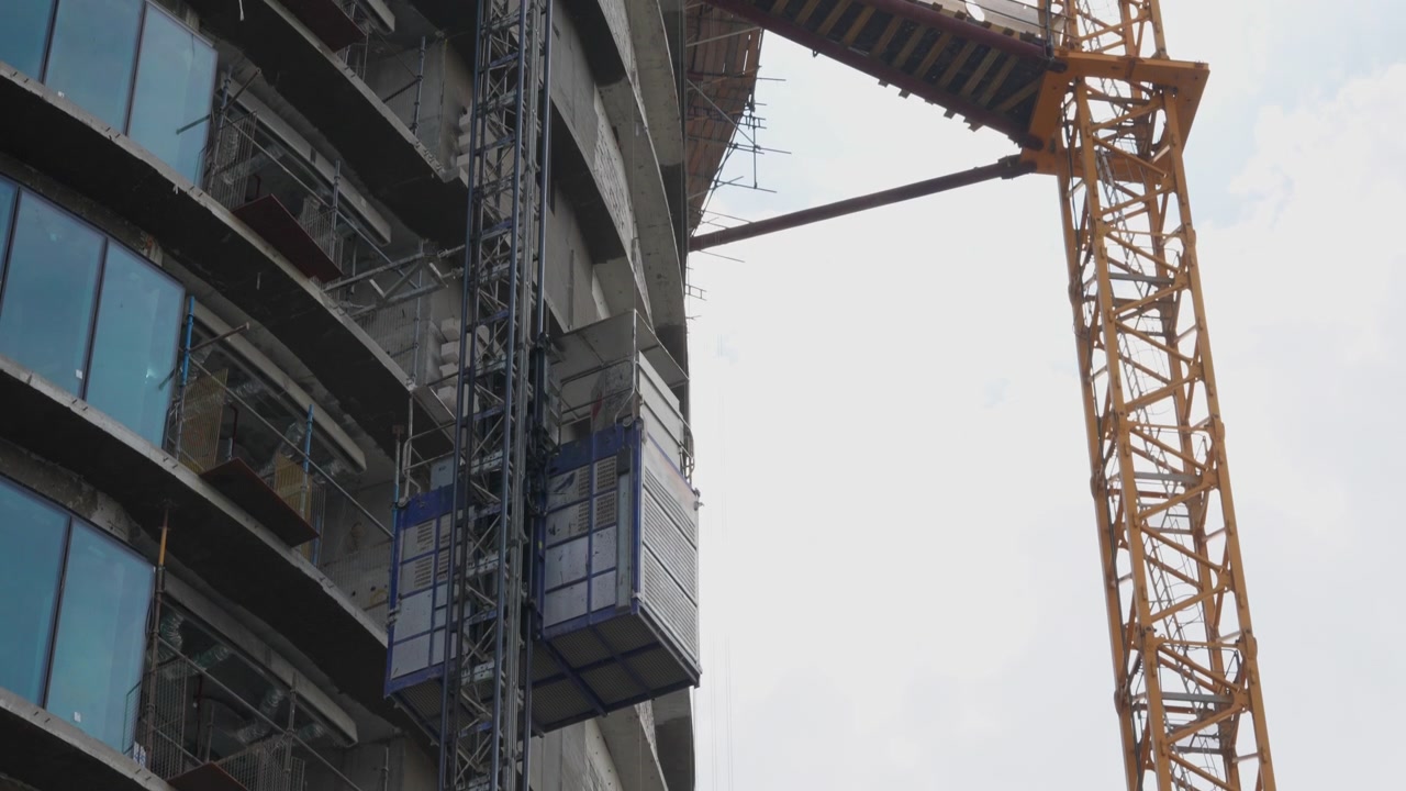 Ascensor de construcción subiendo por el lateral de un edificio de gran altura