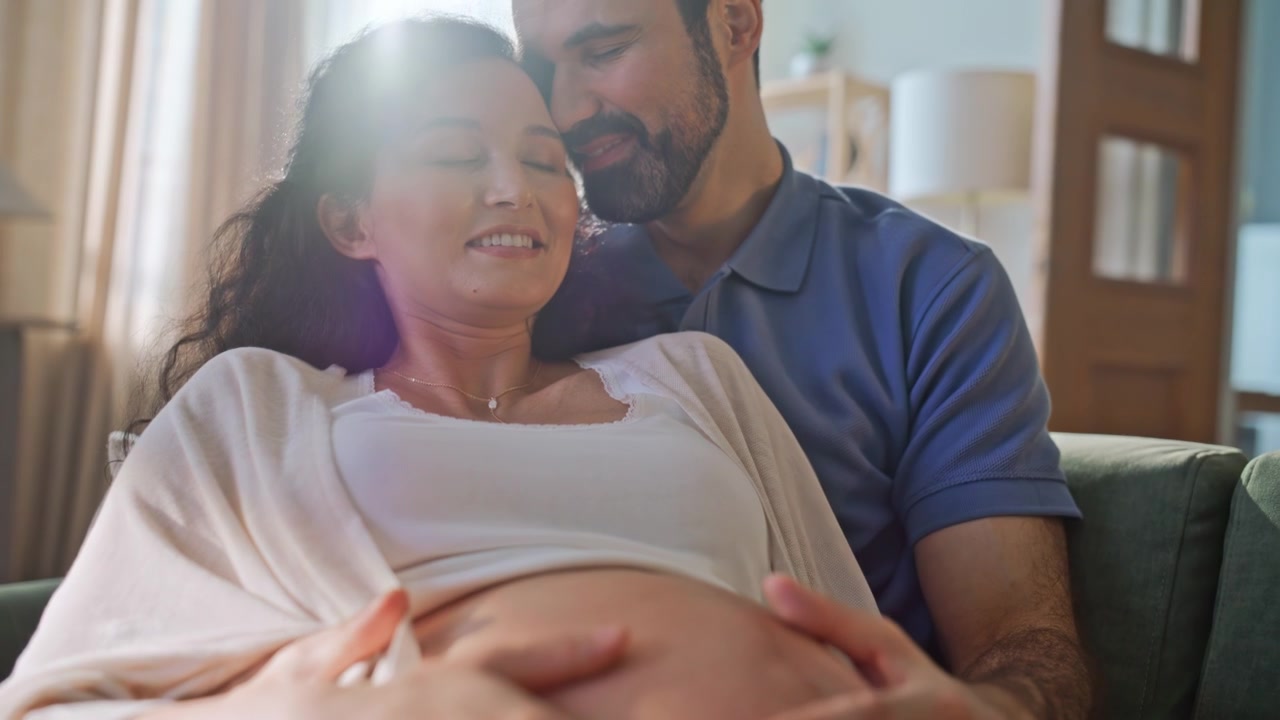 Close up hands touching pregnant belly. Couple caressing baby bump home.
