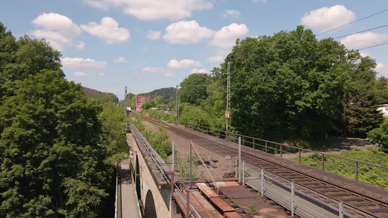 tren de carga que se aleja en la distancia visto desde un viejo caballete de tren oxidado