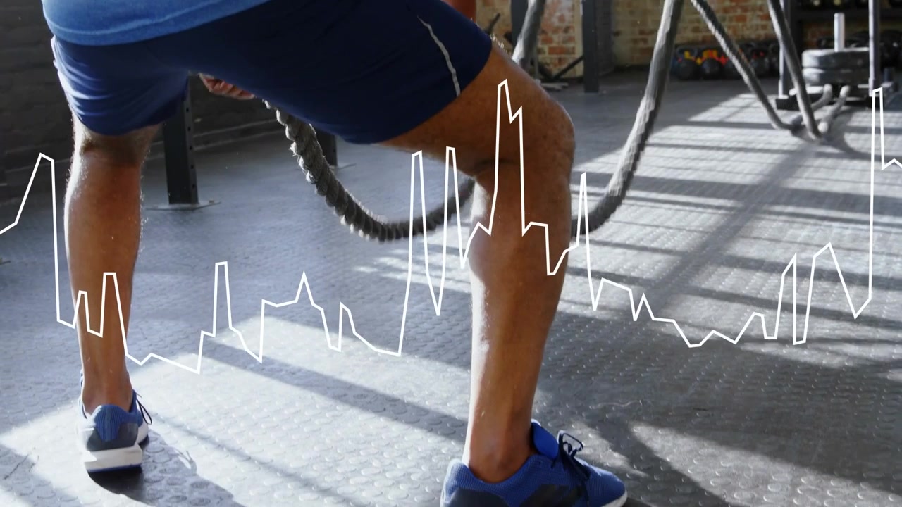 mature man gripping battle ropes and driving waves in gym, waveform mirroring effort for strength