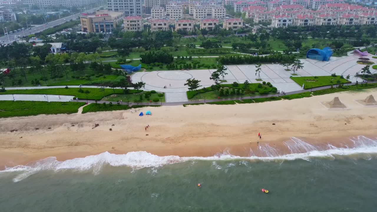 Colorful unique view of sandy beach with sand sculptures, sea waves, natural park and cityscape - high angle aerial view