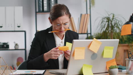 tired sad exhausted businesswoman working on laptop at office with many sticker tasks, panic attack