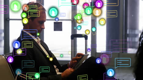 animation of profile and message icons over caucasian businessman using digital tablet at an airport