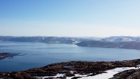 vista aérea del fiordo con aguas tranquilas y vistas a las montañas nevadas en blaheia, noruega
