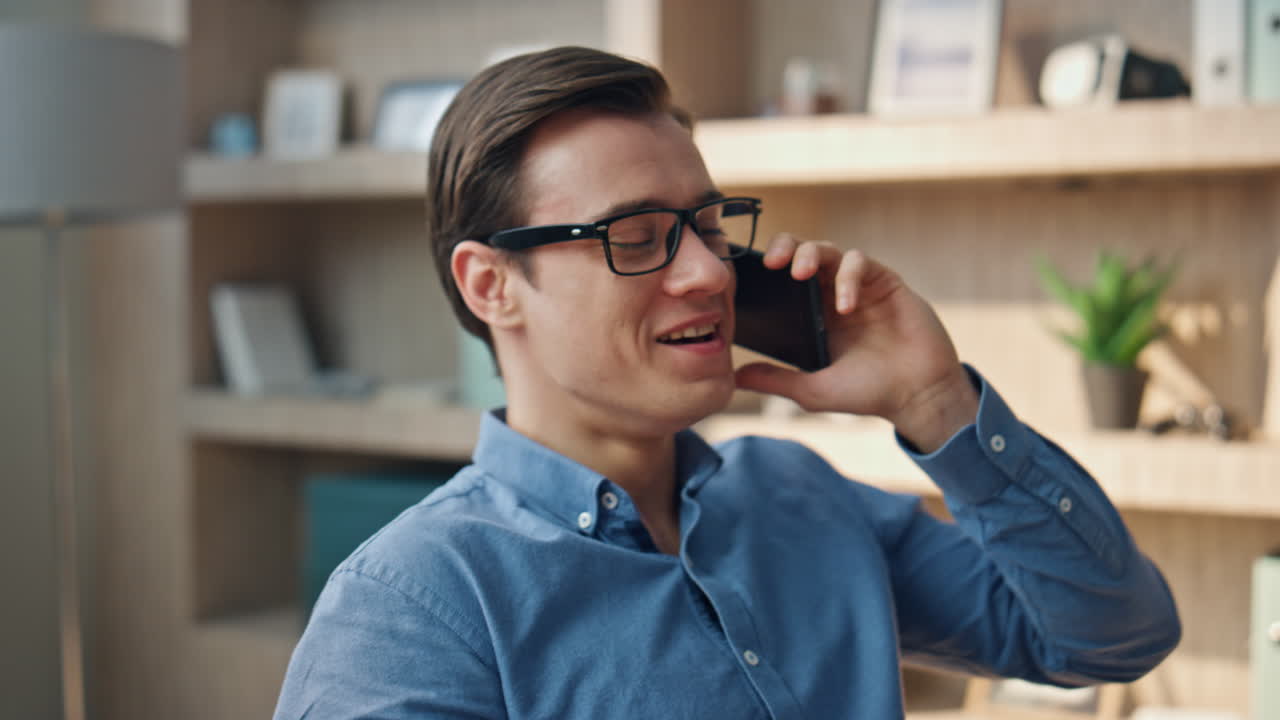 전화하는 프리랜서 사무실에서 공을 던지는 클로즈업. 행복한 사람이 드폰으로 이야기합니다.