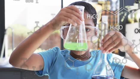 Conducting chemistry experiment, child holding flask with chemical formulas over