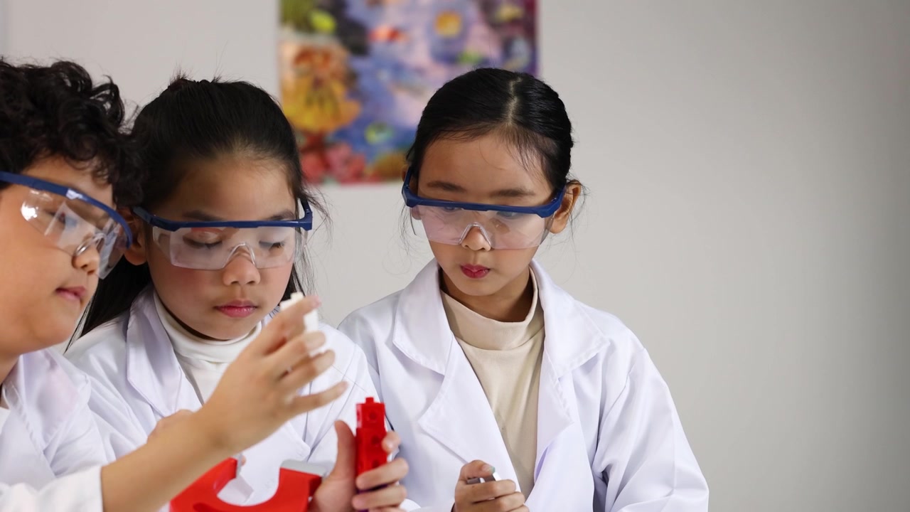 Siswa-siswi Asia yang beragam mengenakan kacamata pengaman dan jas lab saat menjelajahi magnetisme di sekolah