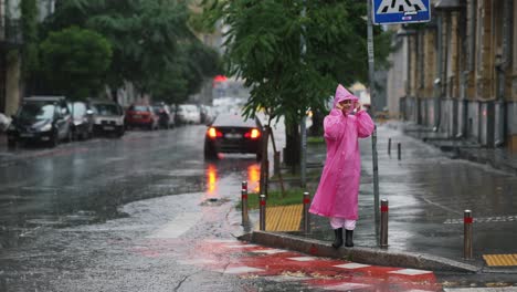 woman in pink raincoat in a rainy city street