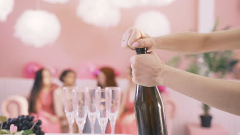 seitenansicht der hände der frau, die eine flasche champagner auf dem tisch öffnen