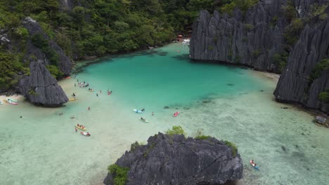 Tourists-kayaking-and-exploring-tropical-emerald-Cadlao-Lagoon-in-El-Nido,-philippines