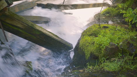 rápidos de agua que se estrellan contra grandes vigas de madera dañadas con rocas cubiertas de musgo 4k prores