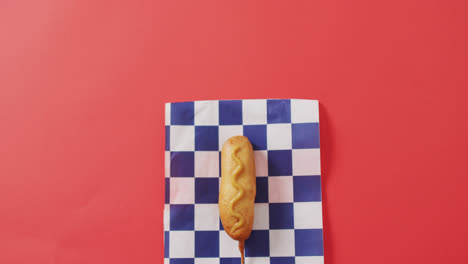 video of corn dog with mustard on a red surface