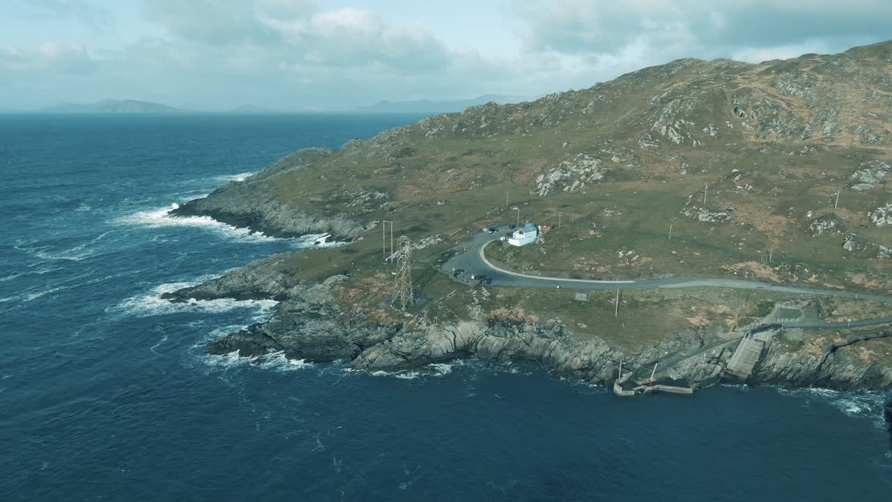ダーシー島の静止した空撮。岩だらけの海岸に波が打ち寄せ、無人のケーブルカーのゴンドラが見える