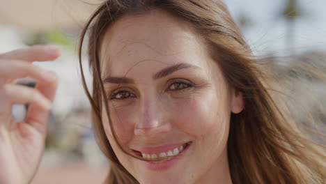 Retrato-De-Cerca-De-Una-Joven-Feliz-Sonriendo-Disfrutando-De-Las-Vacaciones-De-Verano-Corriendo-De-La-Mano-Por-El-Cabello-En-Una-Vibrante-Y-Soleada-Playa-Urbana-Hermosa-Turista-Divirtiéndose-En-Cámara-Lenta