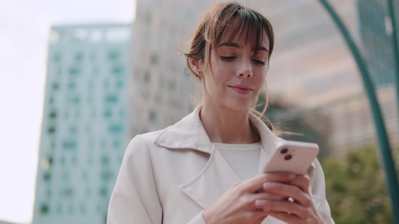 Giovane donna che manda messaggi sullo smartphone in un ambiente urbano