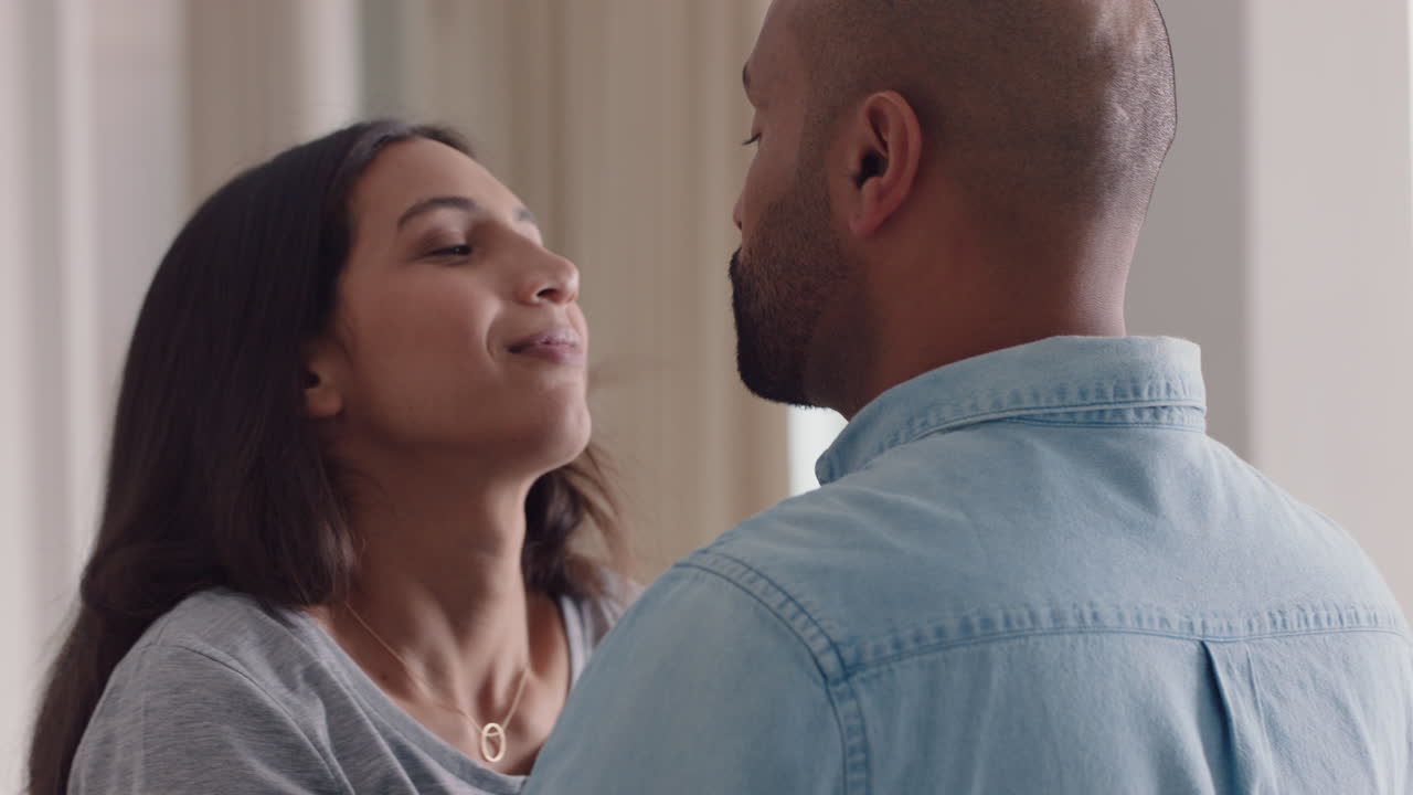 coppia felice di razza mista che abbraccia una bella donna che abbraccia il fidanzato che condivide una relazione d'amore intima a casa