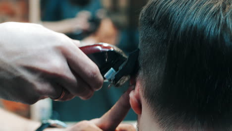 Peluquero-Haciendo-Peinado-Al-Hombre-Usando-Una-Cortadora-Eléctrica-En-La-Barbería