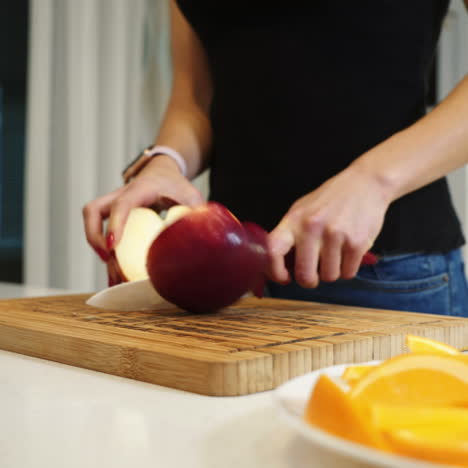 young woman cutting a large red apple on a wooden board. healthy lifestyle. fresh fruits. square video