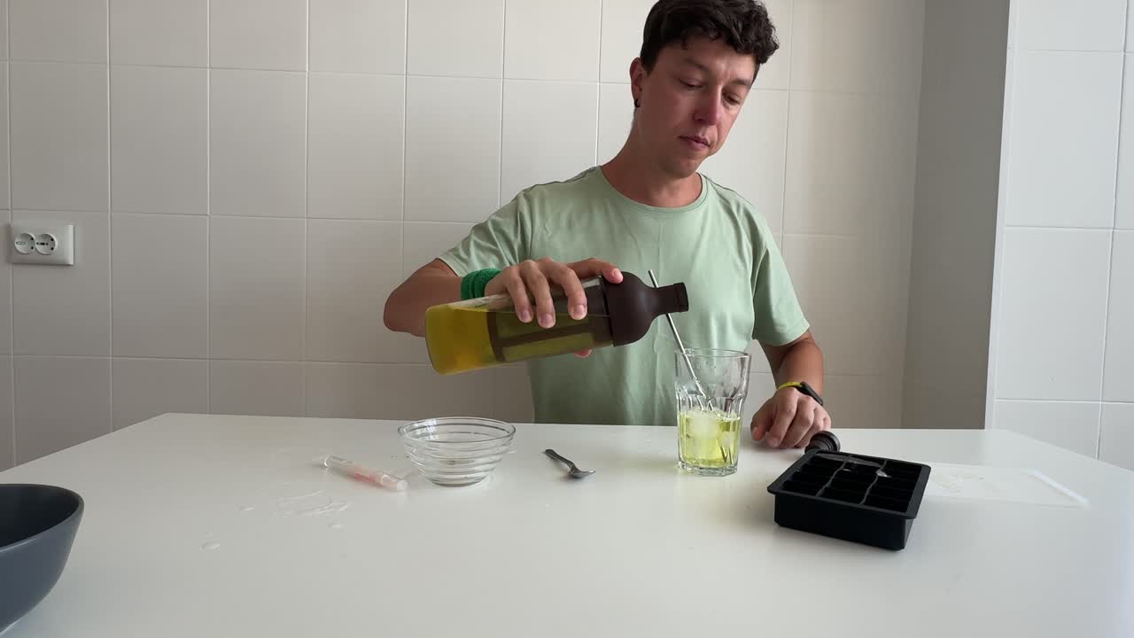 Giovane uomo che mescola e beve una bevanda fredda in cucina