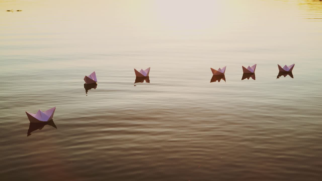 White paper boats float in the lake water at sunset. Origami