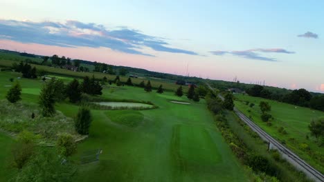 aerial free flying traveling shot of verdant golf course during stunning sunset