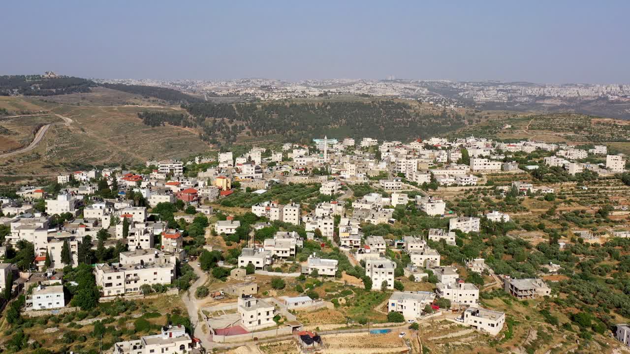 Aerial view of a village or town in a hilly landscape with scattered buildings
