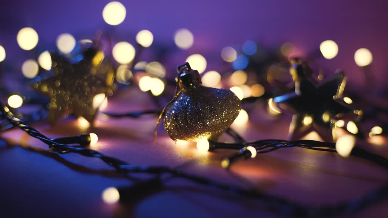 Close-up shot of garland with golden lights and christmas toys on color background. Christmas concept. Home decor. Beautiful bokeh