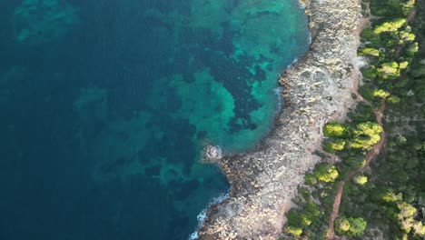 flying on the pristine bay with vegetations over rugged cliffs near sa coma in mallorca spain