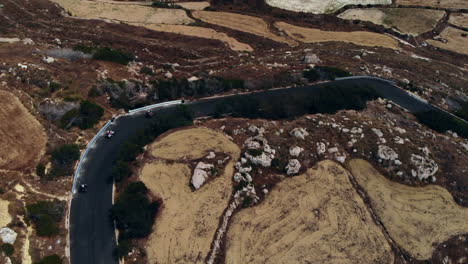 Aerial-Group-Of-Quad-Bikes-Driving-Along-Winding-Coastal-Road-Gozo,-Malta