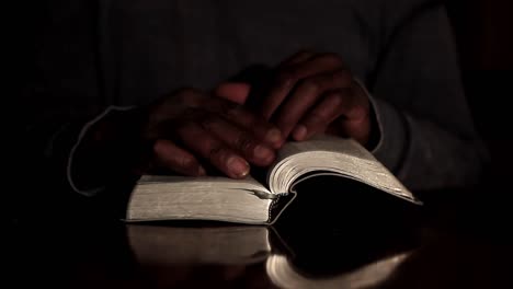 praying to god with hands together with bible and cross caribbean man praying with black background stock video