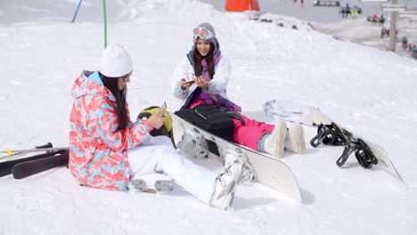 young female friends relaxing with snowboards